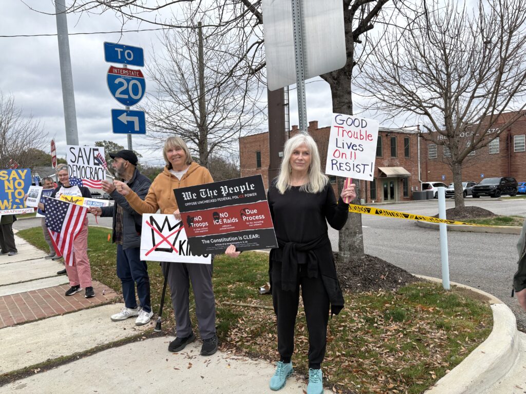 Protestors holding signs protestign Trump and the war